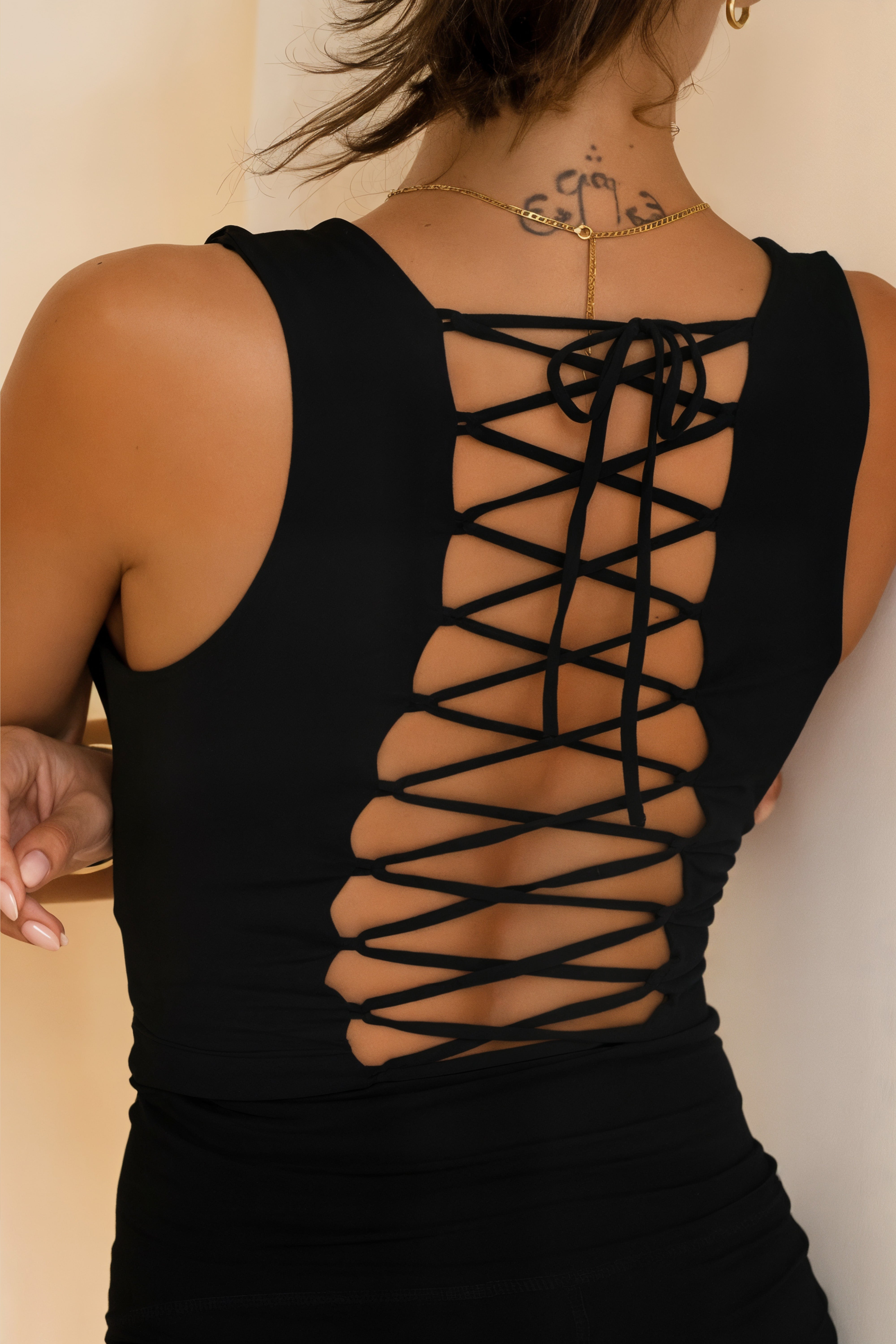 the back of a women wearing a soft strappy yoga tank top in midnight black